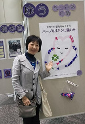 パープルアクション　展示の前に立つ山崎たい子区議